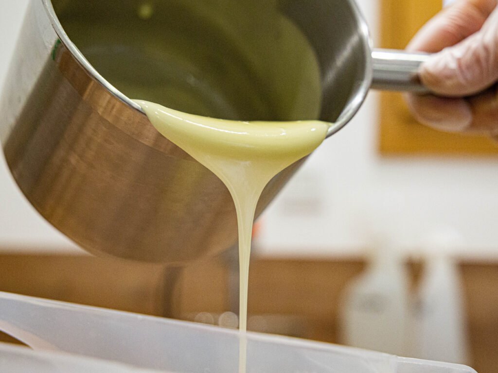 Pâte de savon à froid en train d'être coulé dans un moule lors de l'atelier savon organisé par Savaé